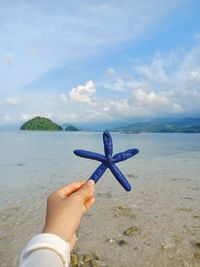 Midsection of person holding sea against sky