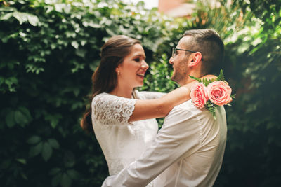 Woman holding rose bouquet against plants