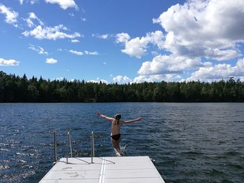 Rear view of man standing in lake against sky