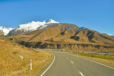 Road amidst mountains against clear sky