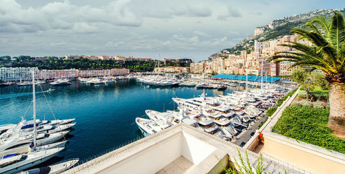 Boats moored at harbor by buildings against sky