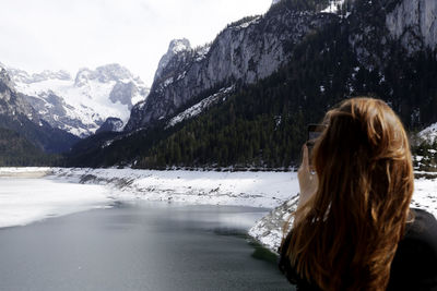 Woman standing by snowcapped mountains during winter