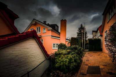 Road amidst buildings against cloudy sky