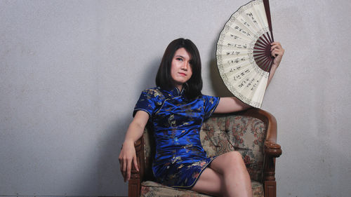 Full length of woman sitting against wall