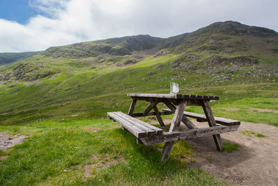 Bench on field against sky