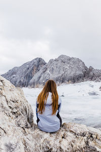 Rear view of woman on snowcapped mountain against sky