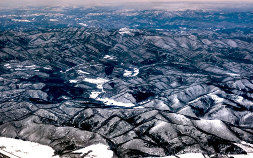 Aerial view of snowcapped landscape against sky during winter