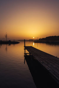 Silhouette wooden pier in lake against sky during sunset