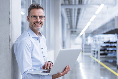 Manager on shop floor of factory using laptop