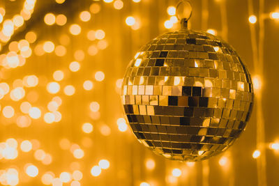 Close-up of disco ball hanging against illuminated lighting equipment