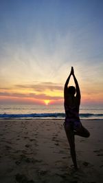 Full length of man doing yoga at beach