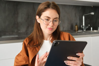 Portrait of young woman using digital tablet at home