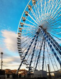 Low angle view of ferris wheel against cloudy sky