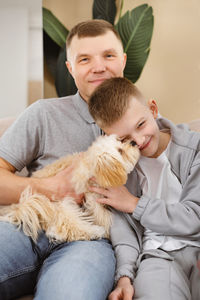 Portrait of boy with dog sitting on sofa at home