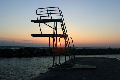 Lifeguard hut on beach against sky during sunset