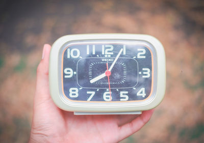 Close-up of hand holding clock