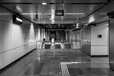 Low angle view of exit sign hanging on ceiling at illuminated station