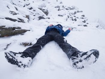 Funny boy laying in snowdrift. kid play game in fresh powder snow on stony hill. snowstorm  weather