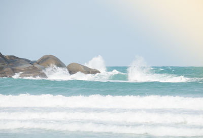 Waves splashing on sea against clear sky