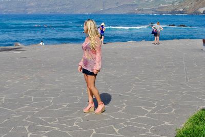 Full length of woman standing at beach during summer