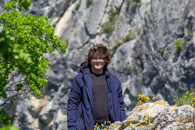 Portrait of young man standing against rock