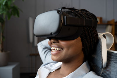 Happy relaxed afro woman in vr googles using virtual reality to relax and reduce stress at workplace