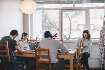 Young roommates sitting while studying in college dorm