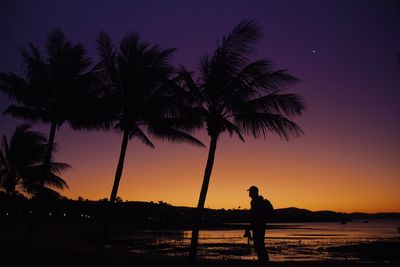 Silhouette palm trees on beach against sky during sunset