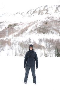 Full length portrait of young woman standing in snow