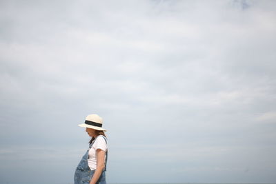 Side view of pregnant women  standing against sky