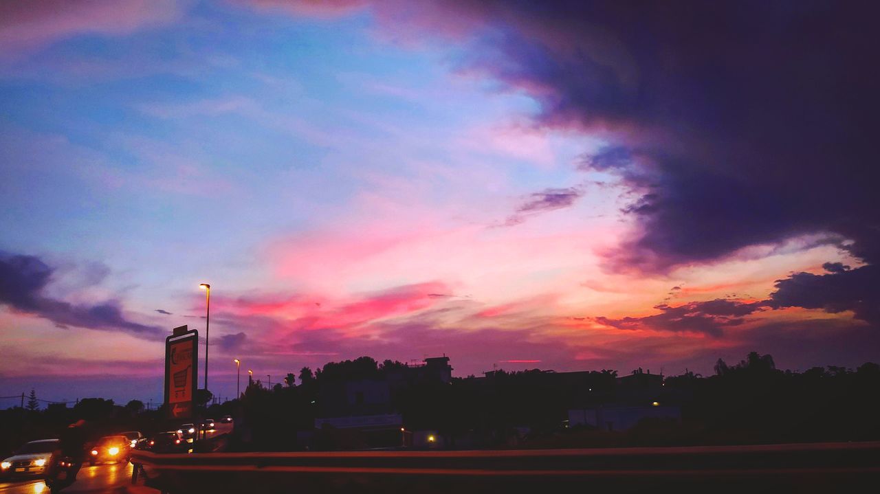 sky, dusk, cloud, architecture, sunset, afterglow, city, transportation, evening, built structure, horizon, street, building exterior, road, illuminated, nature, mode of transportation, car, motor vehicle, no people, night, outdoors, red sky at morning, motion, dramatic sky, travel destinations, land vehicle, travel, city life, building, street light, traffic, landscape