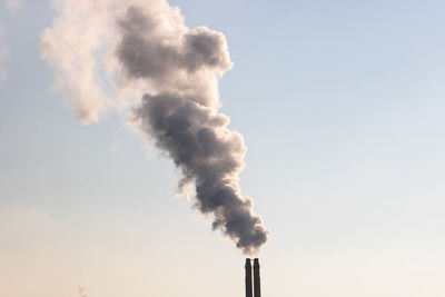 Smoke emitting from chimney against sky