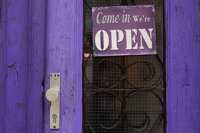 Open sign hanging on purple door