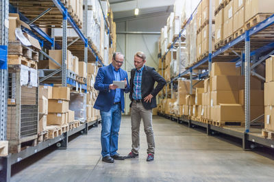 Two managers discussing packaging and shipment in storage hall