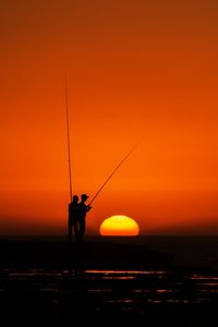 Silhouette fishermen fishing during sunset