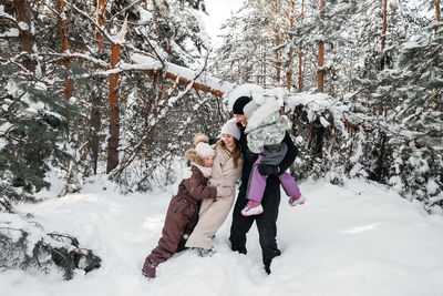 Dad and mom and daughters have fun in the snowy forest. high quality photo