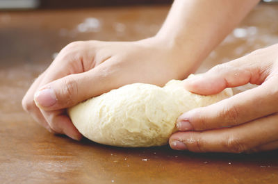 Cropped hand of person kneading dough on table