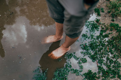 Low section of man standing in puddle