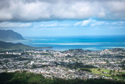 Aerial view of townscape by sea against sky