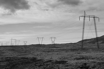 Low angle view of electricity pylon on field against sky