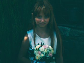 Portrait of woman holding red rose against blue wall