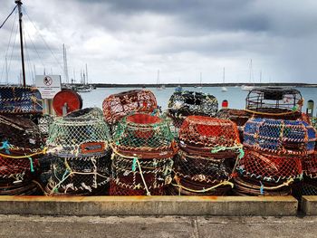Stack of fishing boats moored at harbor against sky