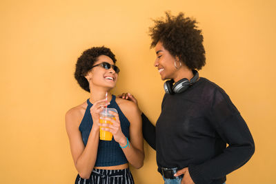 Smiling young woman holding ice cream against orange background