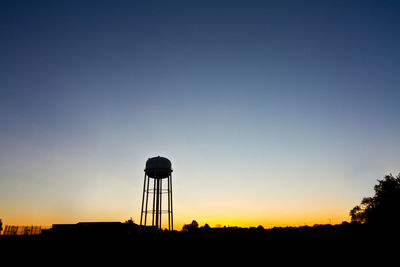 Silhouette water tower against clear sky during sunset