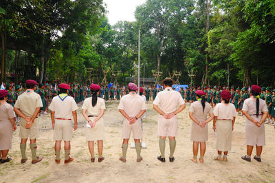 Rear view of people standing against trees