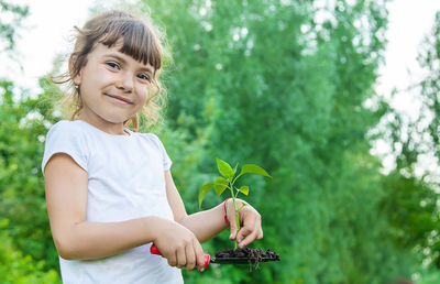 Portrait of smiling girl holding seedling