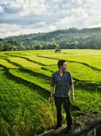 Full length of man standing on railing against farm