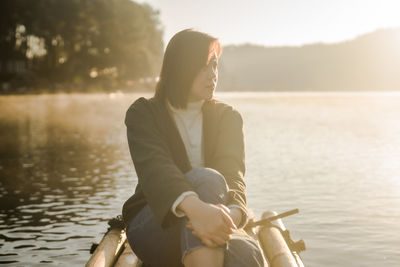 Solo asian woman travel by thai local bamboo boat in tropical forest and lake in autumn season