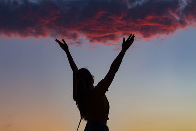 Low angle view of silhouette woman against orange sky