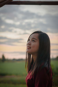 Young woman looking away against sea during sunset